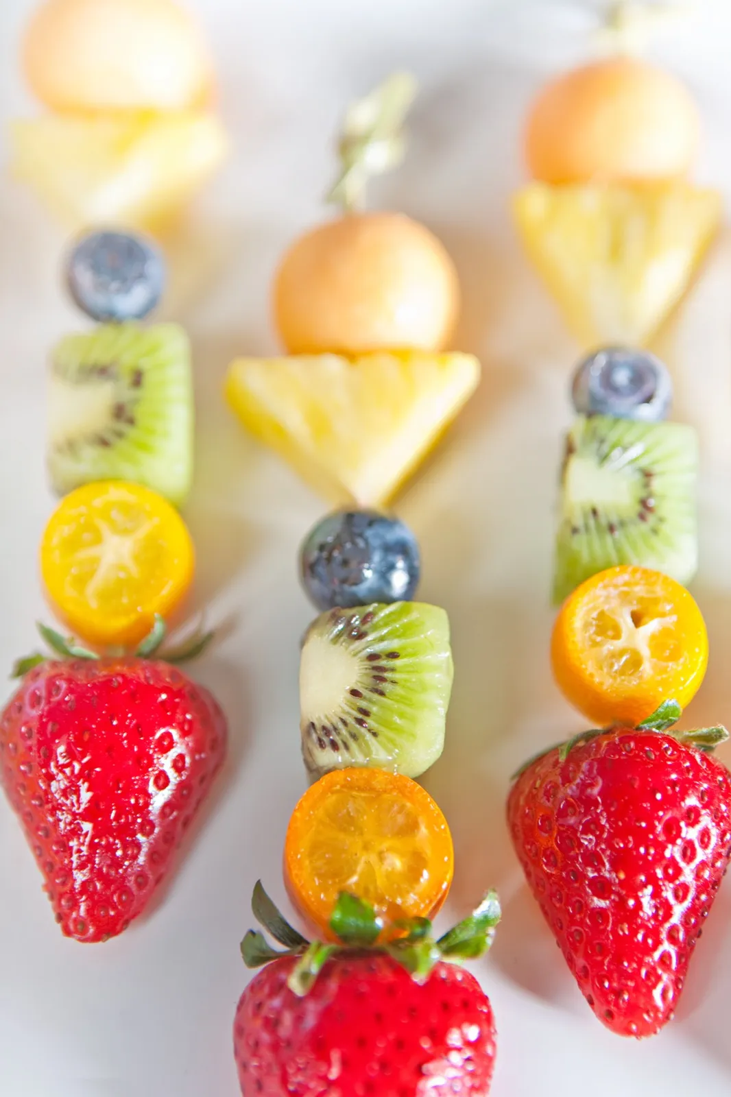 Fresh fruit skewers of strawberry, kumquat, kiwi, blueberry, pineapple, and melon