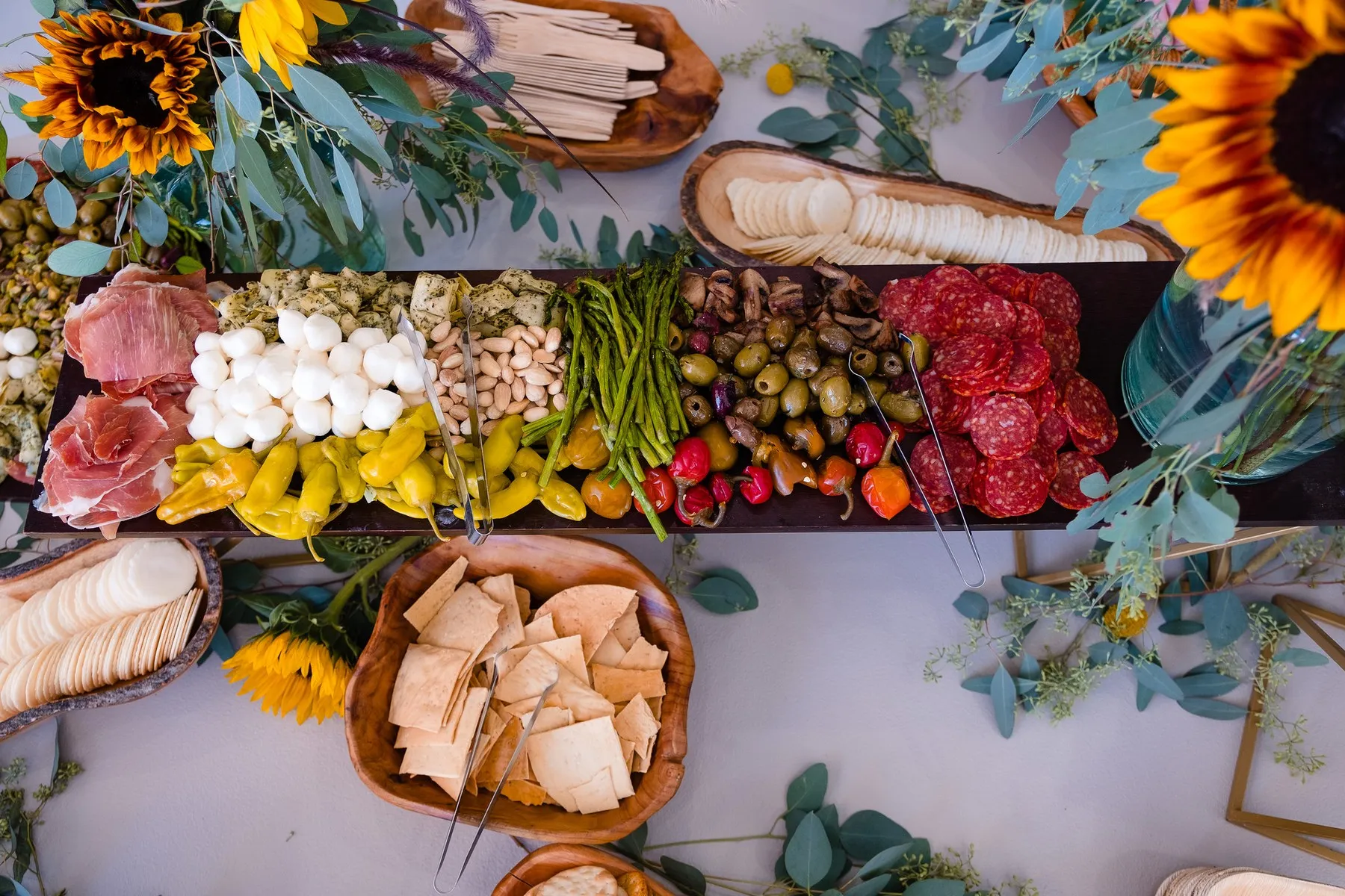 A grazing board with cheeses, charcuterie, fruit and sunflowers