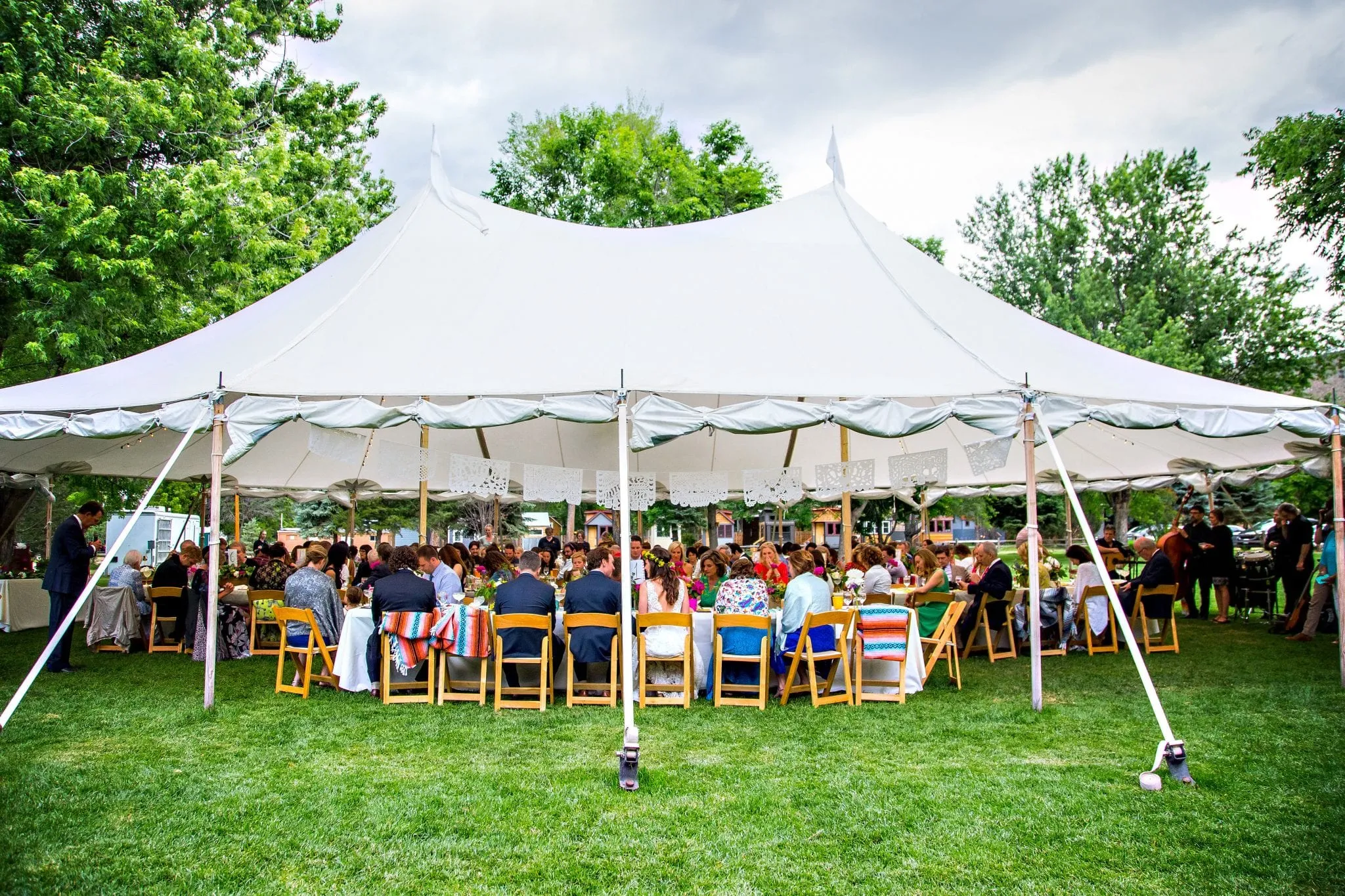 A seated dinner under a sailcloth tent, every table full, guests mid-course